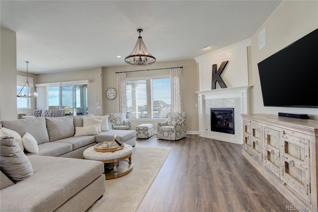 living room with recessed lighting, a notable chandelier, wood finished floors, visible vents, and a glass covered fireplace