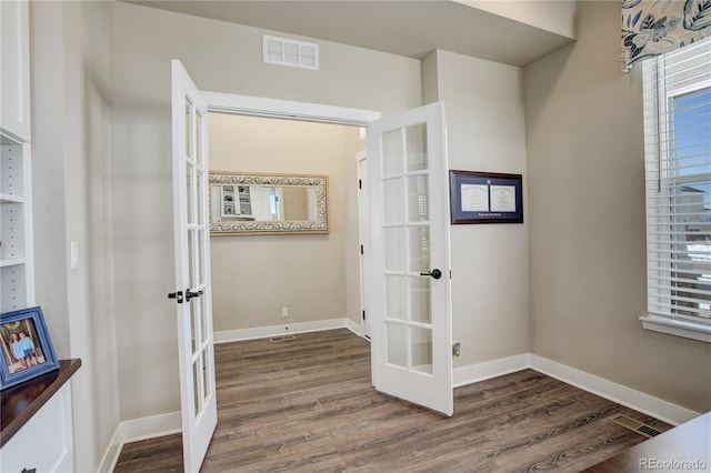 corridor featuring baseboards, visible vents, wood finished floors, and french doors