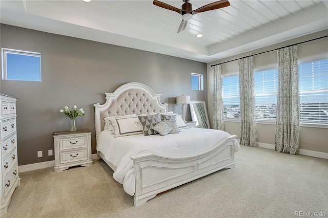 bedroom with baseboards, ceiling fan, a raised ceiling, and light colored carpet