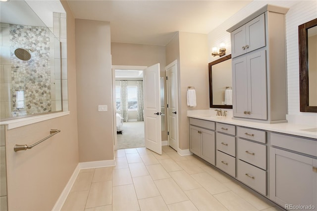 ensuite bathroom with double vanity, a sink, ensuite bath, a walk in shower, and baseboards