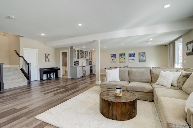 living area with a dry bar, recessed lighting, light wood-style flooring, stairway, and baseboards