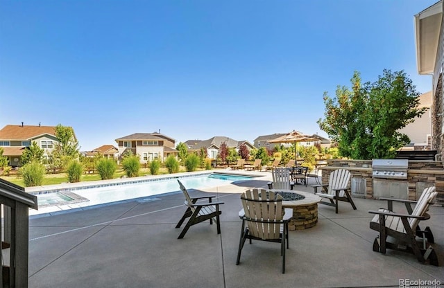 pool with a fire pit, a grill, exterior kitchen, a residential view, and a patio area