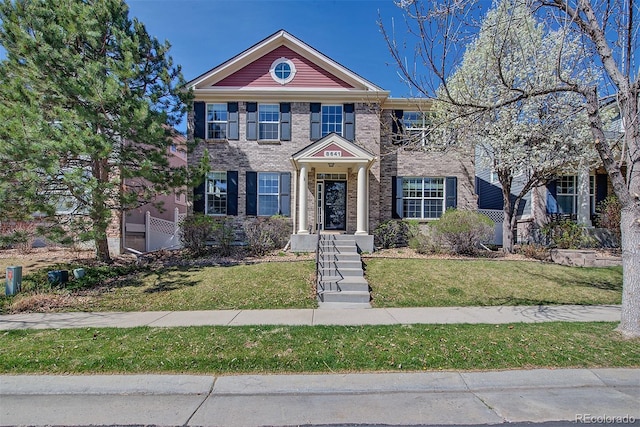 colonial inspired home with brick siding and a front yard