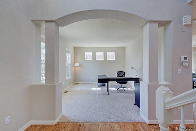 home office with baseboards, arched walkways, wood finished floors, and ornate columns