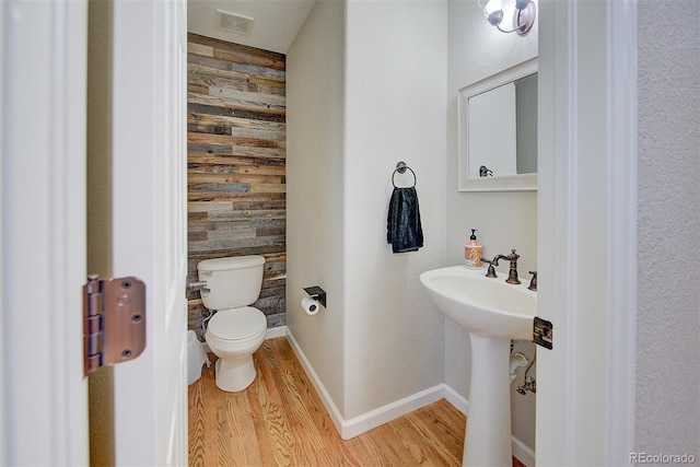 bathroom with toilet, wood finished floors, and visible vents
