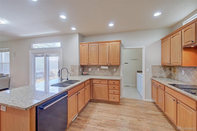 kitchen featuring light wood finished floors, a peninsula, a sink, dishwashing machine, and light stone counters