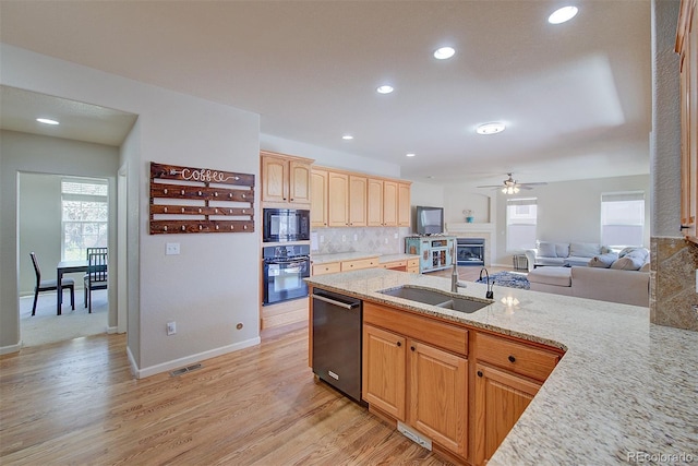 kitchen with plenty of natural light, light wood-type flooring, a sink, and black appliances