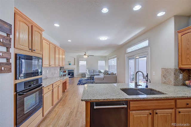 kitchen featuring ceiling fan, light stone countertops, a sink, and black appliances