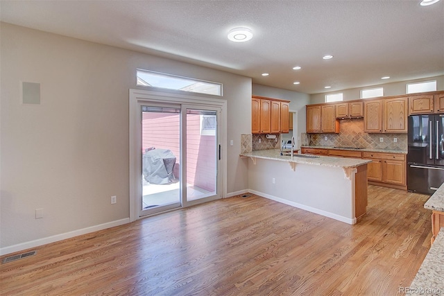 kitchen featuring visible vents, a sink, black appliances, a peninsula, and a kitchen bar