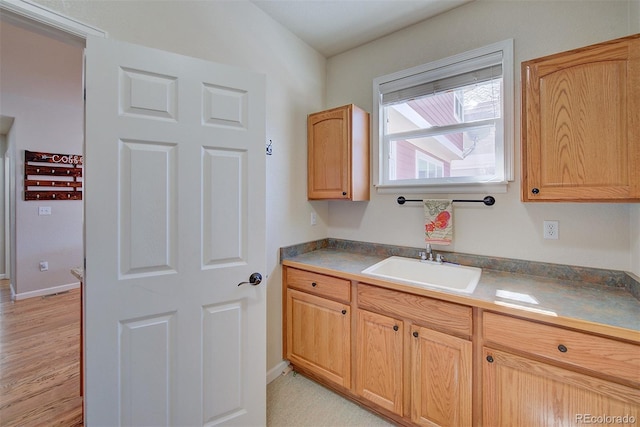 kitchen featuring light wood-style flooring, baseboards, and a sink