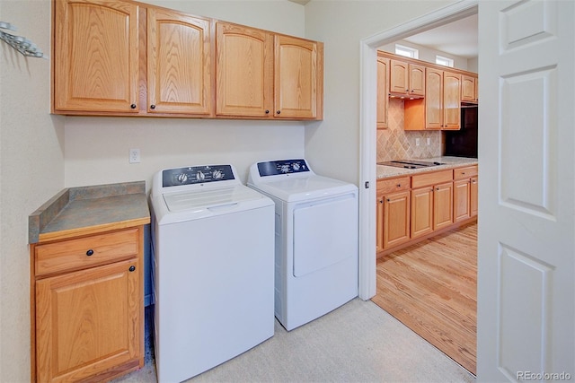 washroom with washer and clothes dryer, light wood-style floors, and cabinet space