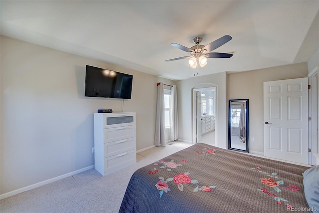 bedroom with ensuite bath, a ceiling fan, baseboards, and light colored carpet
