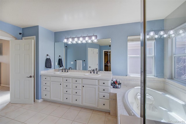 full bathroom featuring tile patterned flooring, a bath, a sink, and double vanity