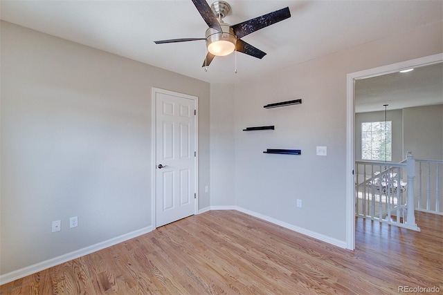 empty room with a ceiling fan, baseboards, and light wood-style floors