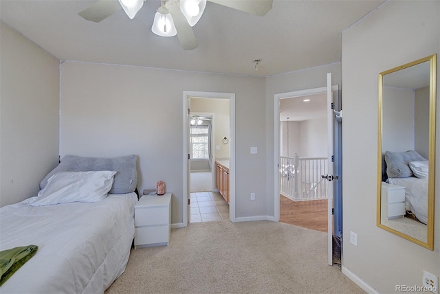 bedroom with light colored carpet, ensuite bath, a ceiling fan, and baseboards