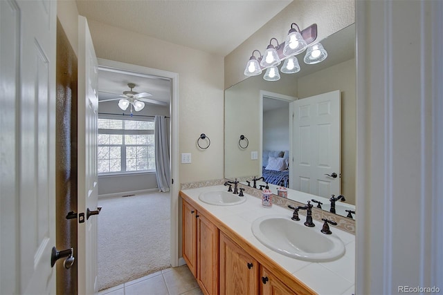 ensuite bathroom with double vanity, connected bathroom, ceiling fan, and a sink