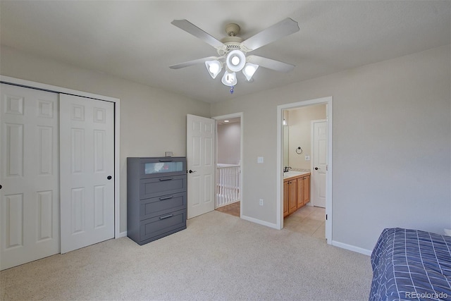 bedroom with light carpet, a sink, baseboards, a closet, and ensuite bath