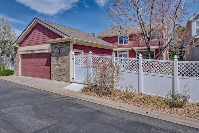 view of front of home featuring brick siding, an attached garage, fence, and driveway