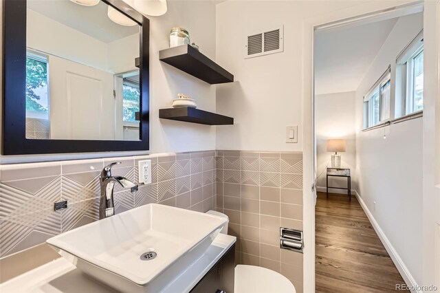 845 Everett St, Lakewood, CO 80215 - half bathroom with healthy amount of natural light, tile walls, wood finished floors, toilet, and wainscoting