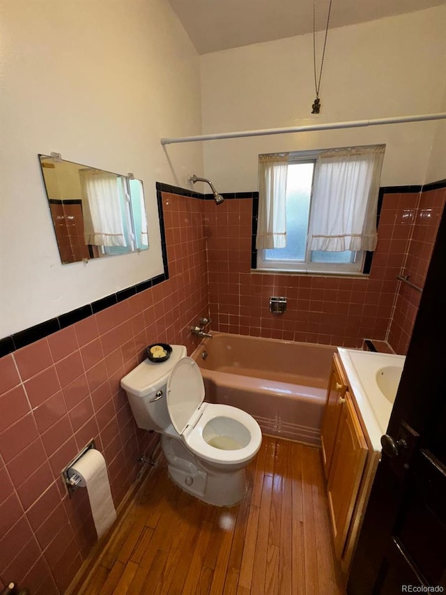 1731 E 25th Ave, Denver, CO 80205 - bathroom with tile walls, vanity, hardwood / wood-style flooring, a wainscoted wall, and tub / shower combination