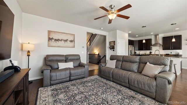 living room with ceiling fan, sink, and dark wood-type flooring