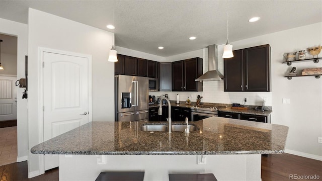 kitchen with sink, wall chimney exhaust hood, hanging light fixtures, stainless steel appliances, and dark hardwood / wood-style floors