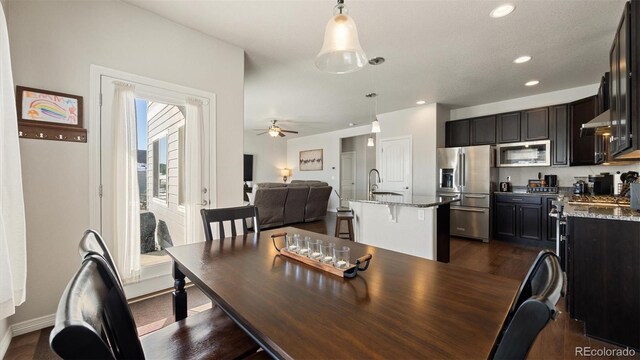 dining area with dark hardwood / wood-style flooring, ceiling fan, and sink