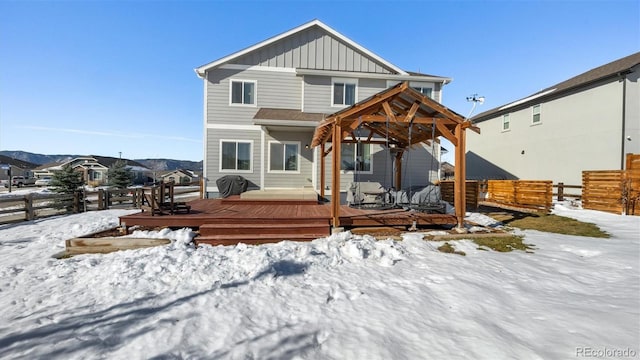 snow covered house with a deck with mountain view