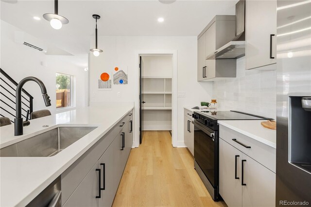 3295 Lawrence St, Denver, CO 80205 - kitchen with stainless steel appliances, wall chimney range hood, gray cabinetry, light wood-style flooring, and a wall mounted AC