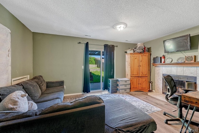 3730 Hazelwood Ct, Colorado Springs, CO 80918 - home office with light wood-style floors, a tile fireplace, and a textured ceiling