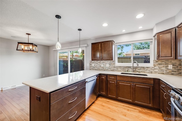 kitchen with sink, decorative light fixtures, kitchen peninsula, and appliances with stainless steel finishes