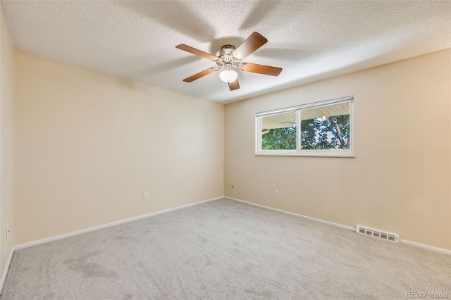 empty room with ceiling fan, carpet flooring, and a textured ceiling