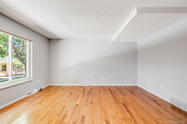 unfurnished room featuring a textured ceiling and light wood-type flooring