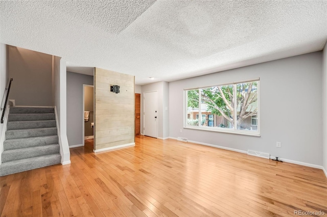 unfurnished living room with light wood-type flooring and a textured ceiling