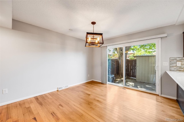 interior space featuring a textured ceiling, an inviting chandelier, and light hardwood / wood-style flooring