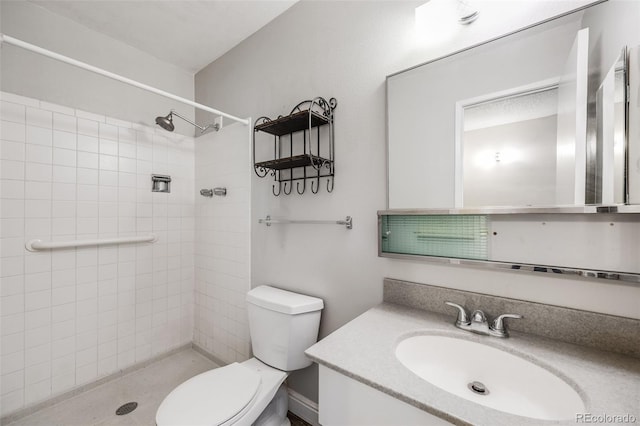 bathroom featuring toilet, vanity, and a tile shower