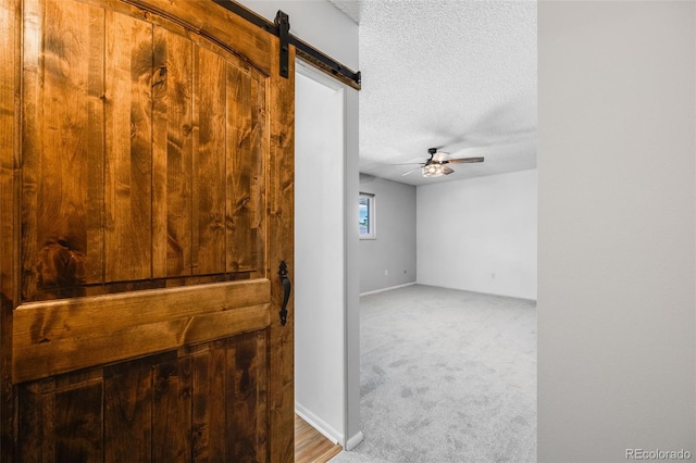 hall featuring a textured ceiling, carpet, and a barn door