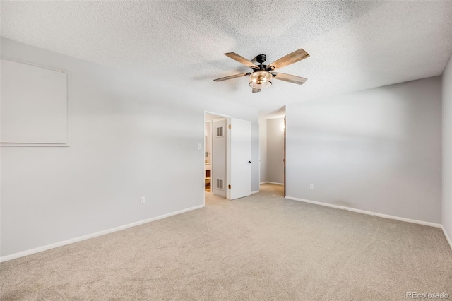 spare room with ceiling fan, light colored carpet, and a textured ceiling