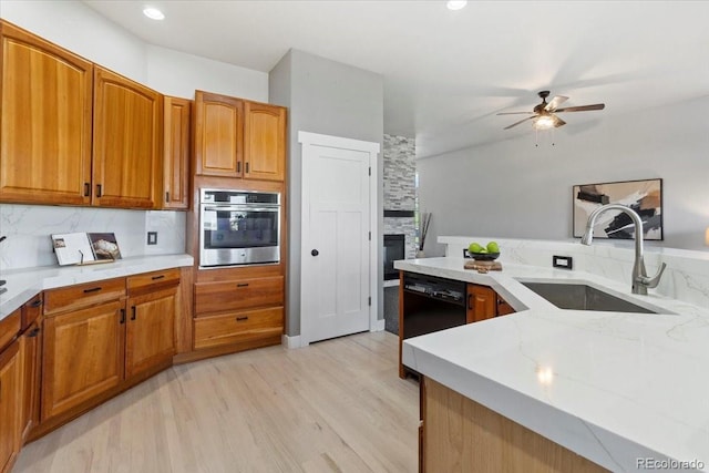 828 Rabbit Run Dr, Golden, CO 80401 - kitchen with oven, a ceiling fan, light wood-style flooring, brown cabinetry, and a fireplace