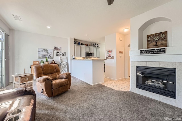 carpeted living room with a tile fireplace