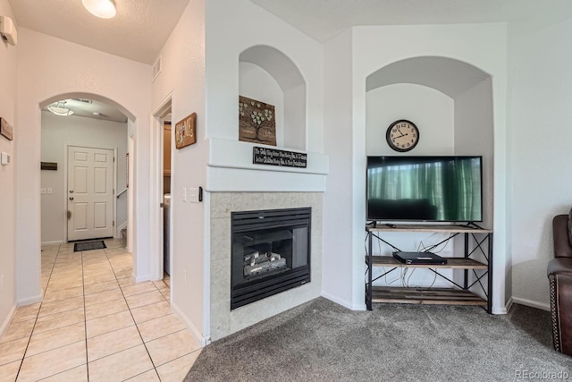 unfurnished living room featuring a textured ceiling, a tile fireplace, and light tile patterned floors