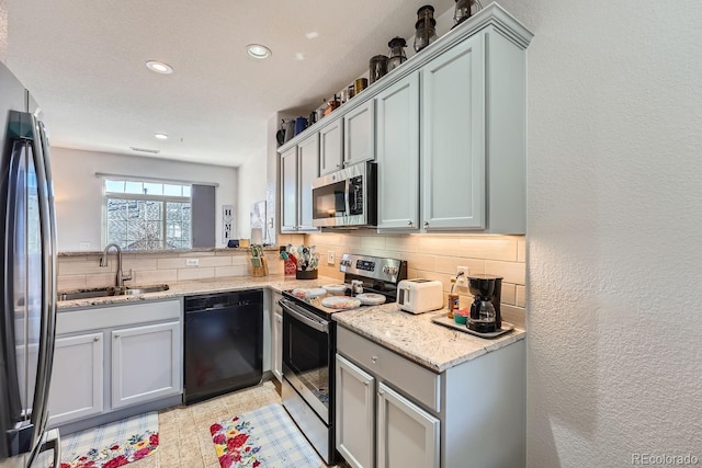 kitchen with sink, decorative backsplash, light stone counters, and black appliances