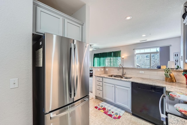 kitchen with sink, electric range oven, stainless steel refrigerator, black dishwasher, and light stone countertops