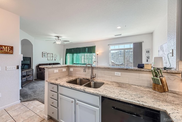 kitchen featuring dishwasher, sink, light tile patterned floors, light stone counters, and kitchen peninsula