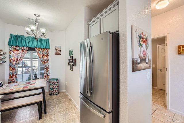 kitchen with decorative light fixtures, stainless steel fridge, a chandelier, and gray cabinetry