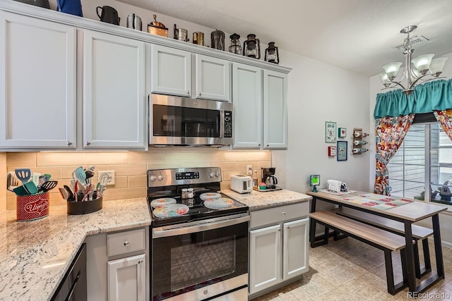 kitchen with an inviting chandelier, decorative light fixtures, stainless steel appliances, light stone countertops, and backsplash