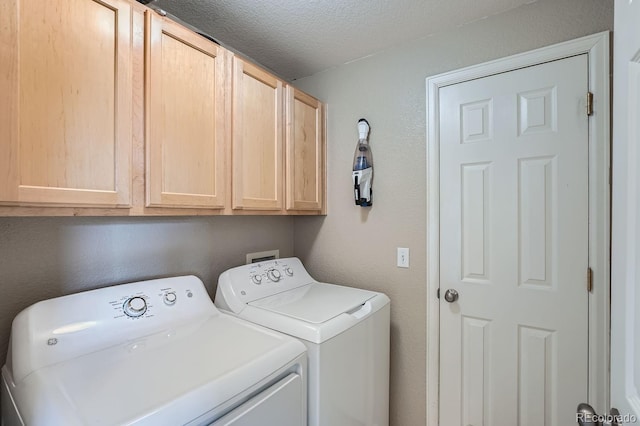 clothes washing area with washer and clothes dryer, cabinets, and a textured ceiling