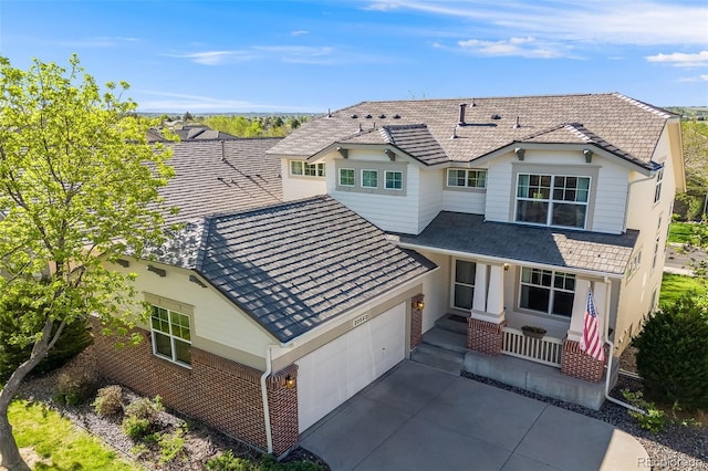 traditional-style home featuring concrete driveway, an attached garage, covered porch, and brick siding
