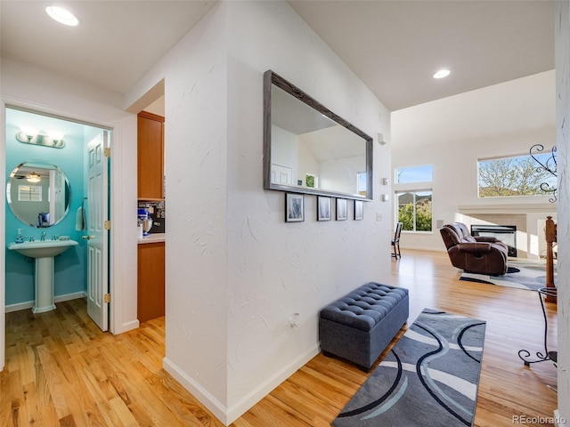hallway with light wood finished floors, baseboards, and recessed lighting