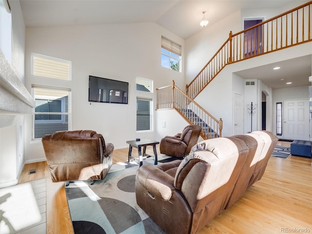 living room with high vaulted ceiling, stairs, wood finished floors, baseboards, and arched walkways